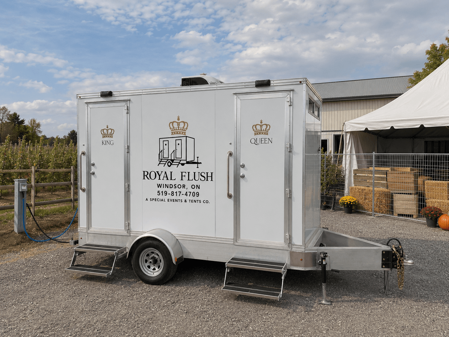 Royal Flush Windsor restroom trailer on site at a farm with an event tent and seasonal produce in the background