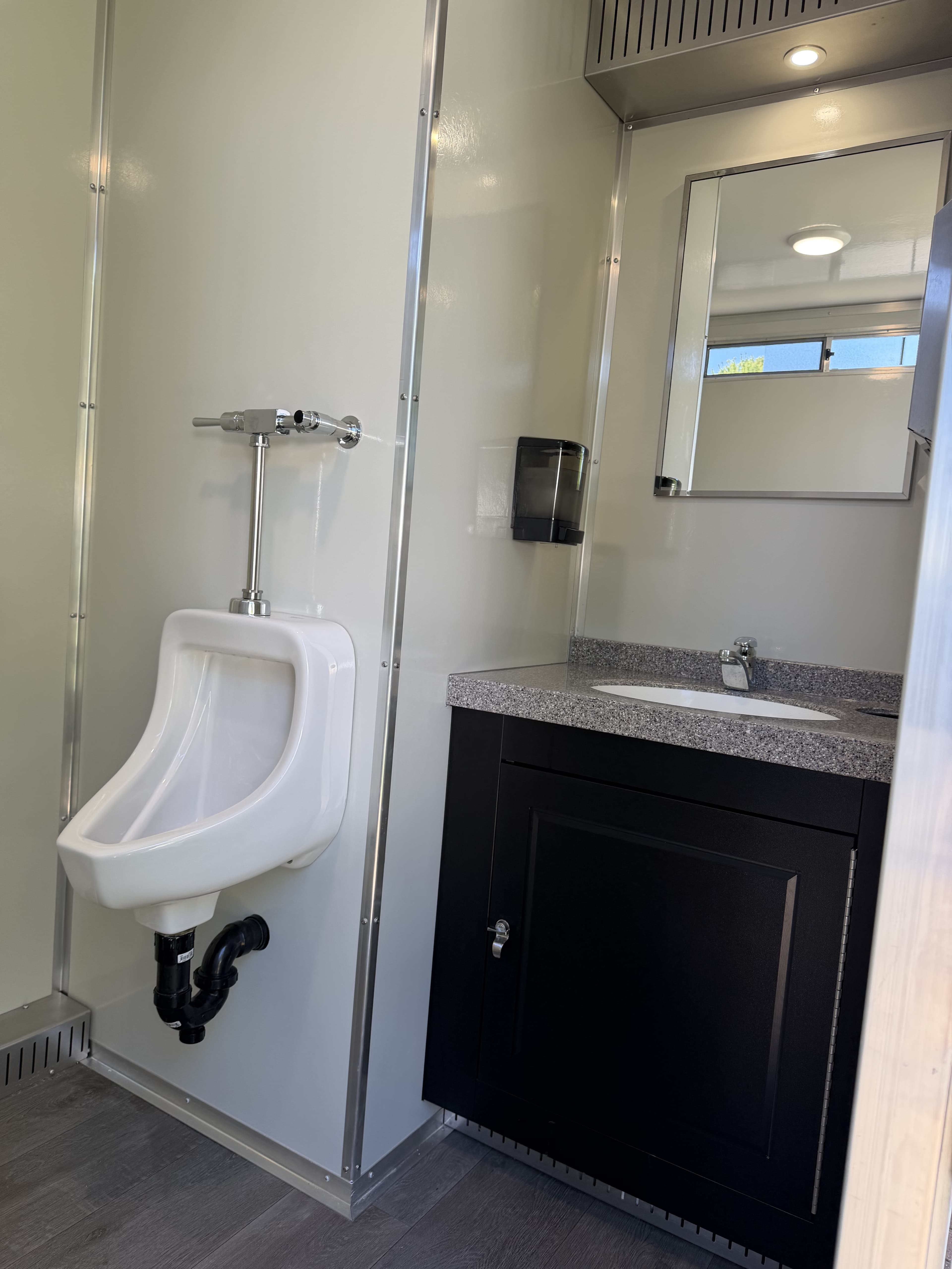 Interior finishing details including wood-look flooring, brushed-metal trim, urinal, and vanity