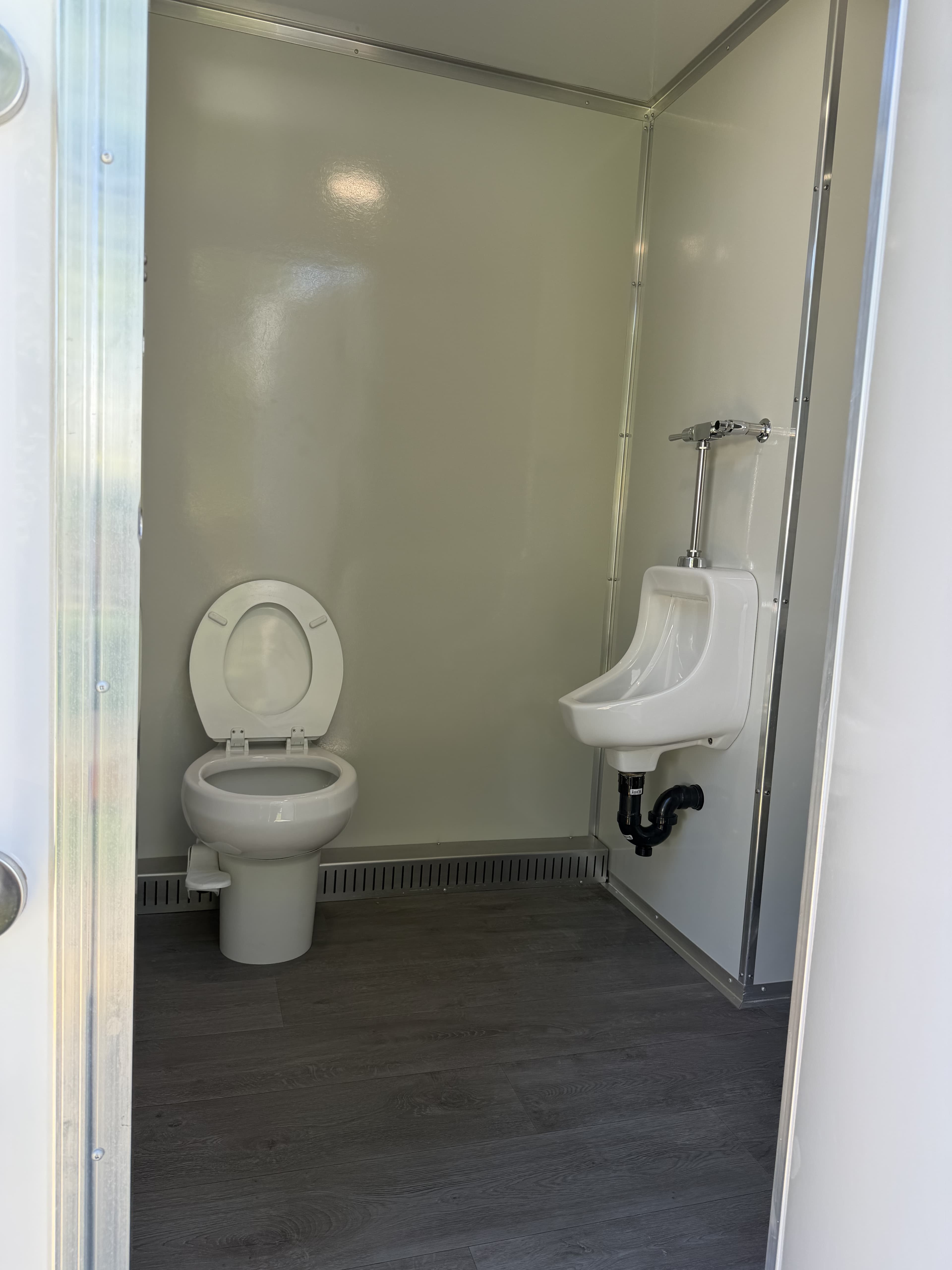 Interior of the King suite showing a residential-style flush toilet and a dedicated urinal over wood-look flooring