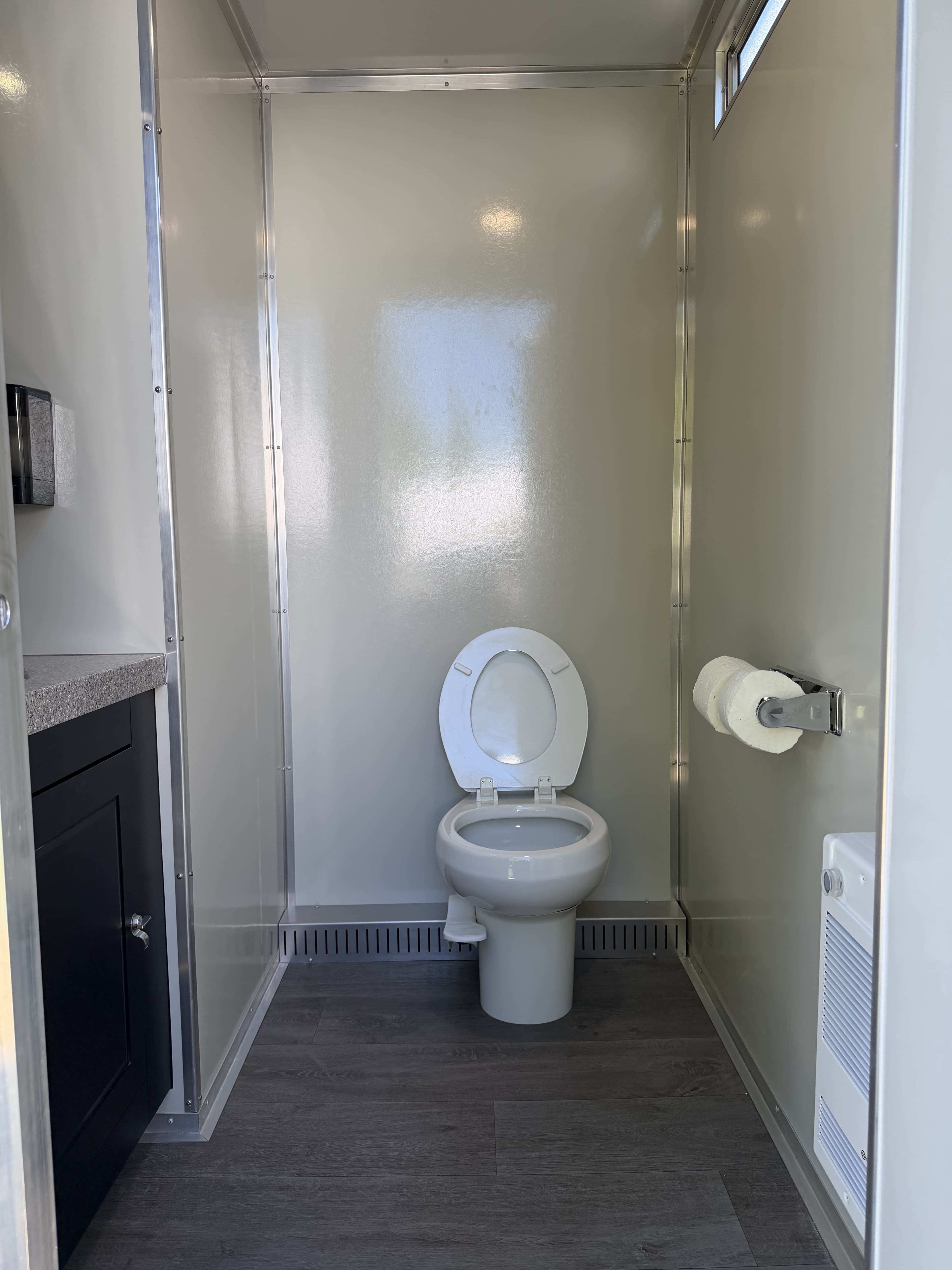 Interior of the Queen suite with a private flush toilet, toilet paper holder, and vanity